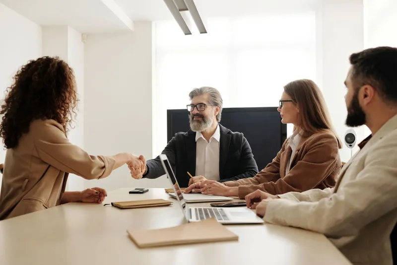 Two professionals shaking hands across a boardroom table